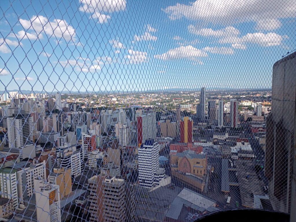 Vista da cidade de São Paulo através de rede de proteção instalada em sacada